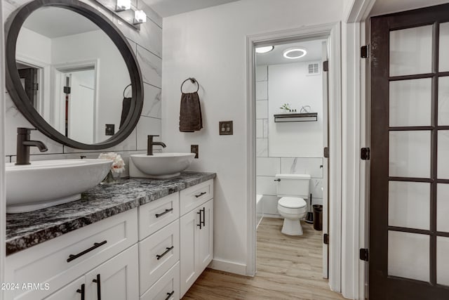 bathroom with vanity, toilet, wood-type flooring, and tile walls