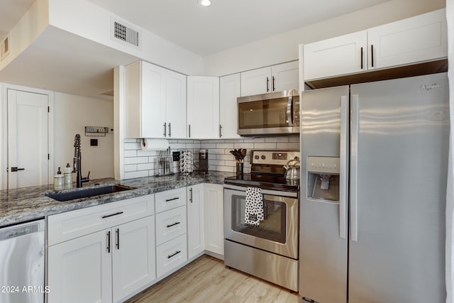 kitchen featuring sink, appliances with stainless steel finishes, white cabinets, and stone countertops