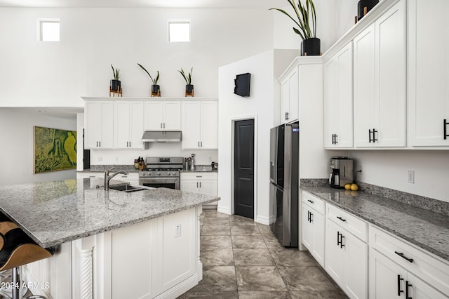 kitchen with sink, a breakfast bar area, a kitchen island with sink, white cabinets, and appliances with stainless steel finishes