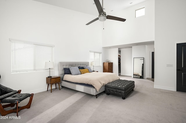 carpeted bedroom with multiple windows, ceiling fan, and a high ceiling