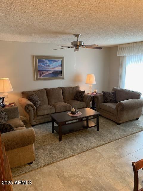 tiled living room with ceiling fan and a textured ceiling