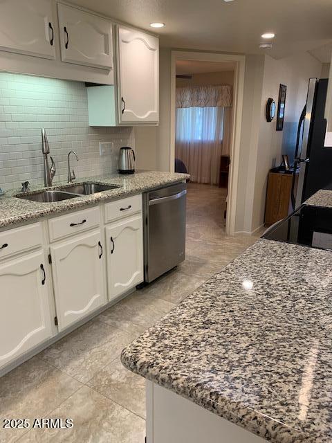 kitchen featuring white cabinetry, sink, decorative backsplash, stainless steel appliances, and light stone countertops