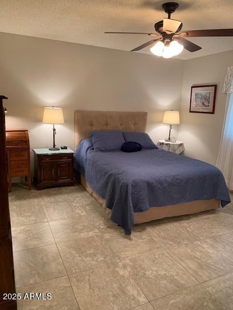 tiled bedroom with ceiling fan and a textured ceiling