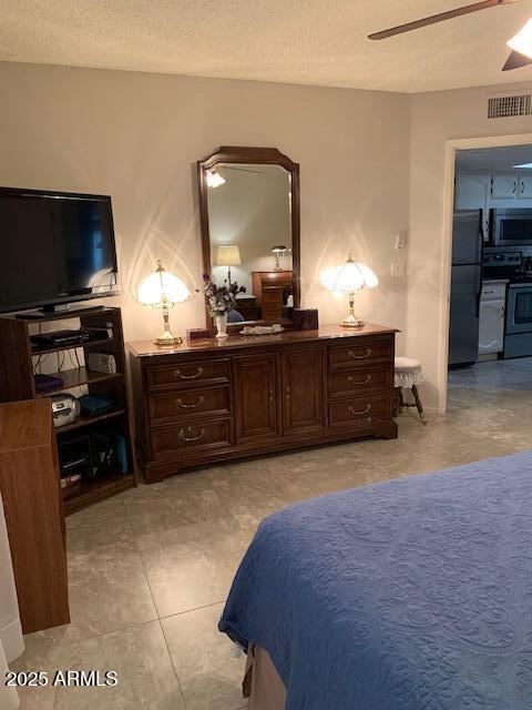 tiled bedroom featuring black fridge, a textured ceiling, and ceiling fan