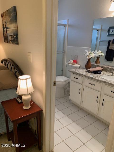 bathroom featuring vanity, a shower with shower door, tile patterned floors, and toilet