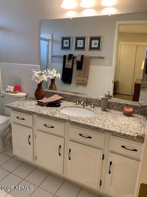 bathroom featuring walk in shower, vanity, toilet, and tile patterned flooring