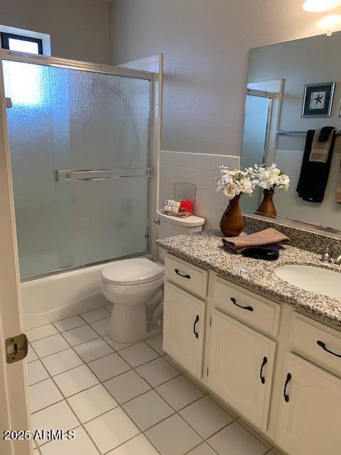 full bathroom featuring toilet, vanity, combined bath / shower with glass door, and tile patterned flooring