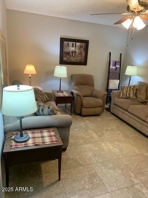 living room featuring ceiling fan and a textured ceiling