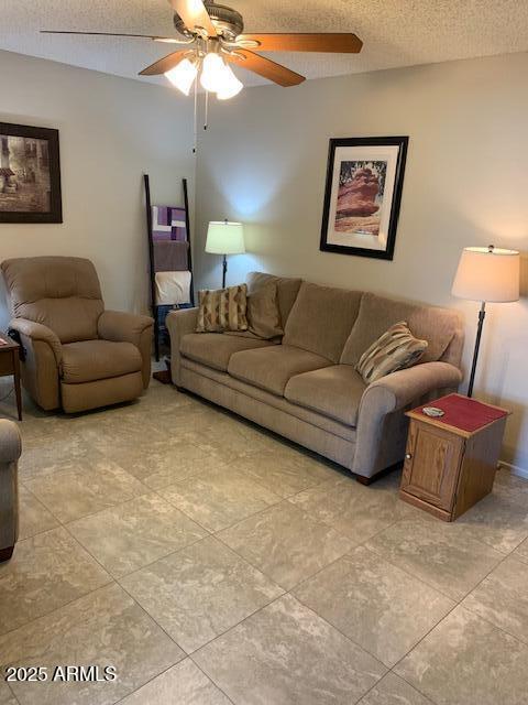 living room featuring ceiling fan and a textured ceiling