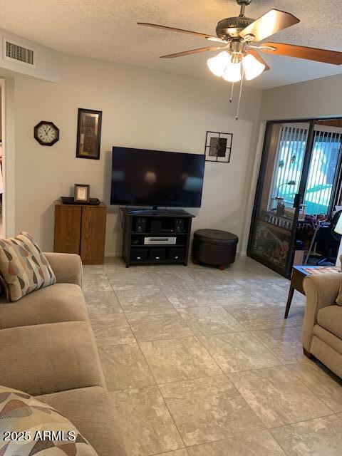 living room featuring ceiling fan and a textured ceiling