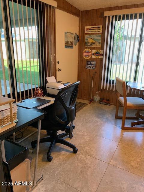 office area with light tile patterned floors and wooden walls