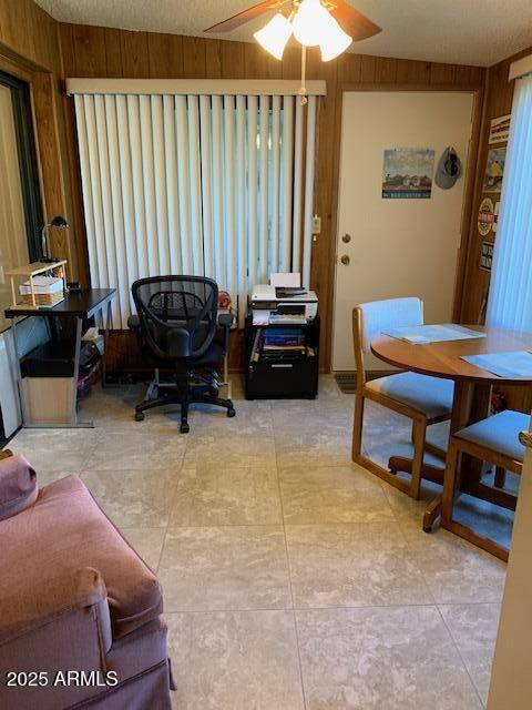 interior space with ceiling fan and wooden walls