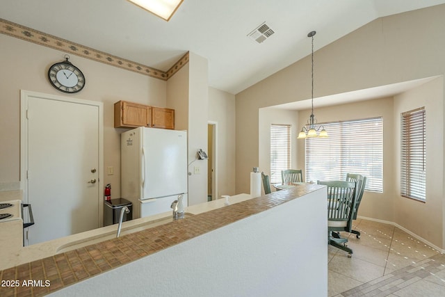 kitchen with pendant lighting, sink, light tile patterned floors, vaulted ceiling, and white fridge