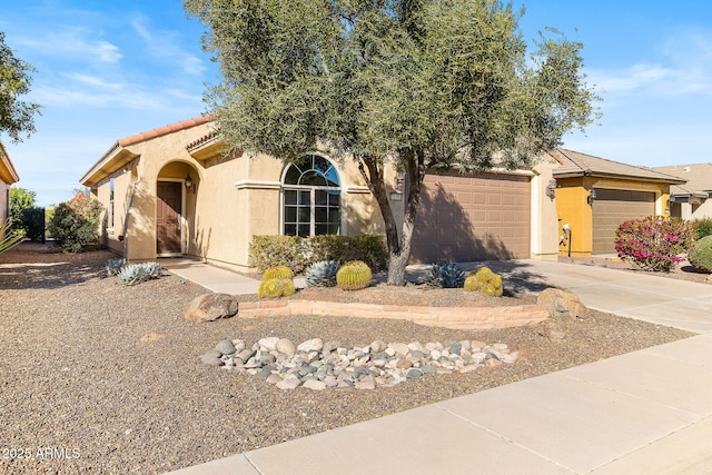 view of front of home with a garage, concrete driveway, a tile roof, and stucco siding