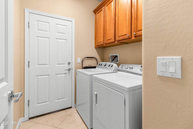 laundry area with cabinets, light tile patterned flooring, and washer and dryer