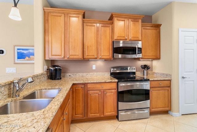 kitchen with light tile patterned flooring, a sink, appliances with stainless steel finishes, light stone countertops, and brown cabinetry