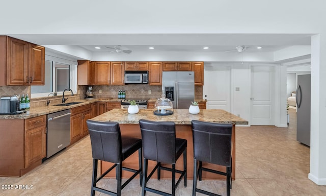 12682 N 80th Pl, Scottsdale, AZ 85260 - kitchen with stainless steel appliances, ceiling fan, a kitchen breakfast bar, brown cabinetry, and recessed lighting