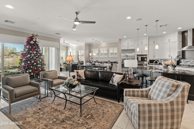 tiled living room featuring crown molding, sink, and ceiling fan