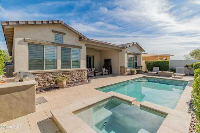 back of house with a patio area, ceiling fan, exterior kitchen, and a pool with hot tub