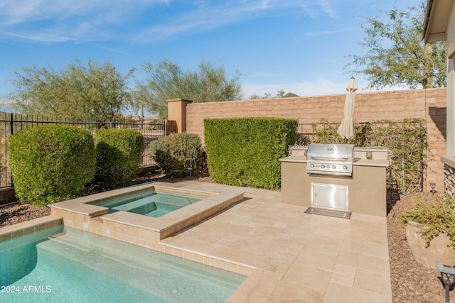 view of swimming pool with an in ground hot tub, an outdoor kitchen, and grilling area