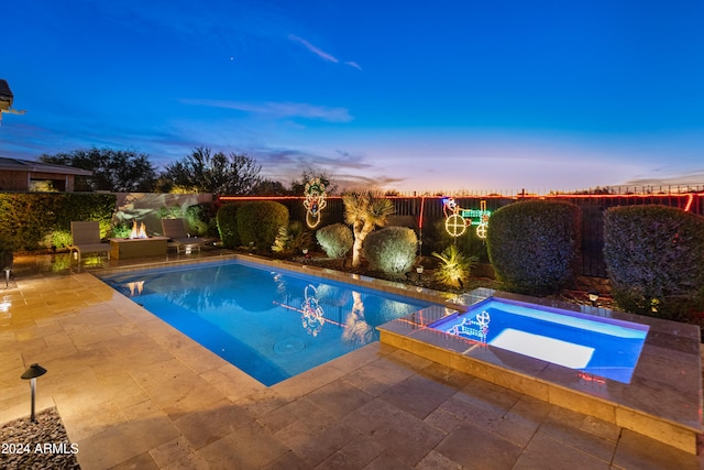 pool at dusk featuring an in ground hot tub and a patio area