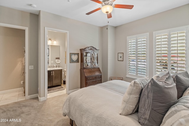 bedroom with ceiling fan, light colored carpet, and connected bathroom