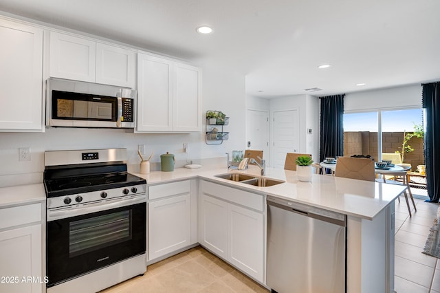 kitchen with a sink, stainless steel appliances, a peninsula, and white cabinets