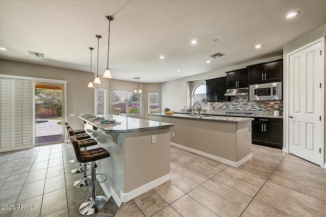 18207 W Sells Dr, Goodyear, AZ 85395 - kitchen featuring a kitchen island with sink, appliances with stainless steel finishes, tasteful backsplash, light tile patterned flooring, and recessed lighting