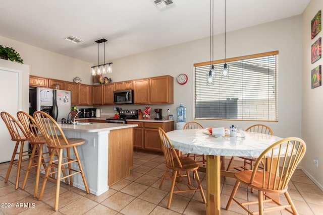 kitchen with hanging light fixtures, a center island with sink, light tile patterned floors, a notable chandelier, and stainless steel appliances