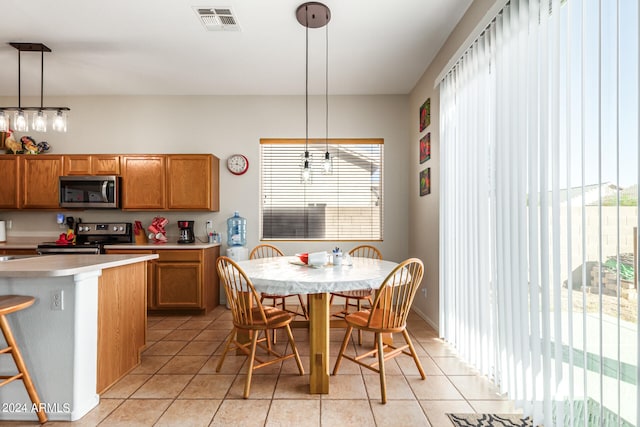 kitchen featuring appliances with stainless steel finishes, decorative light fixtures, a kitchen island, and light tile patterned floors