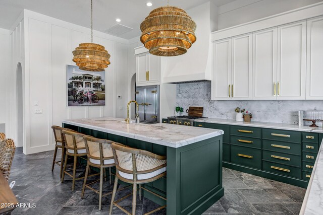 2339 E Virgo Pl, Chandler, AZ 85249 - kitchen with green cabinetry, backsplash, a kitchen island with sink, white cabinetry, and a breakfast bar