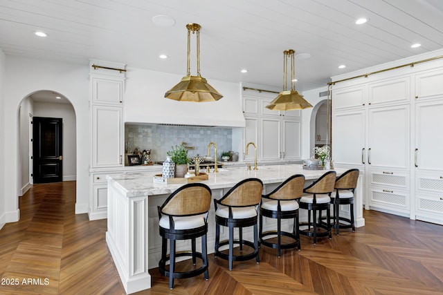 2339 E Virgo Pl, Chandler, AZ 85249 - kitchen with arched walkways, recessed lighting, white cabinetry, an island with sink, and a breakfast bar