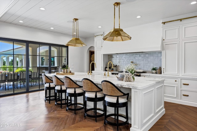 2339 E Virgo Pl, Chandler, AZ 85249 - kitchen with recessed lighting, white cabinets, light stone counters, an island with sink, and tasteful backsplash