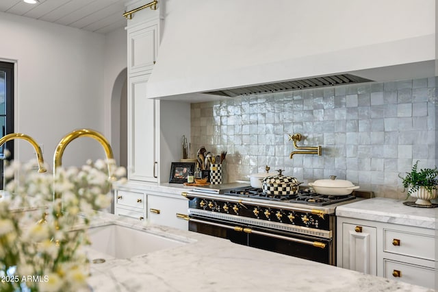 2339 E Virgo Pl, Chandler, AZ 85249 - kitchen with range with two ovens, custom range hood, tasteful backsplash, light stone counters, and white cabinetry