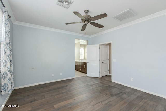 empty room featuring dark wood-type flooring, visible vents, and crown molding