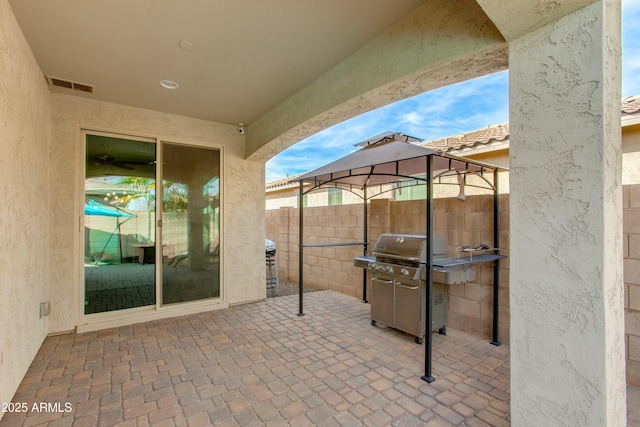 view of patio with visible vents, a grill, a gazebo, and fence