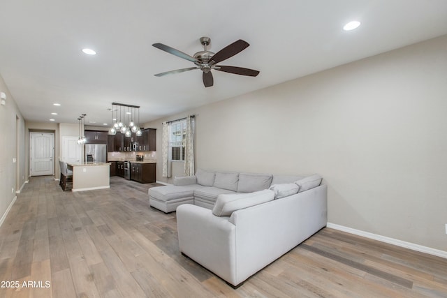 living room with baseboards, recessed lighting, a ceiling fan, and light wood-style floors