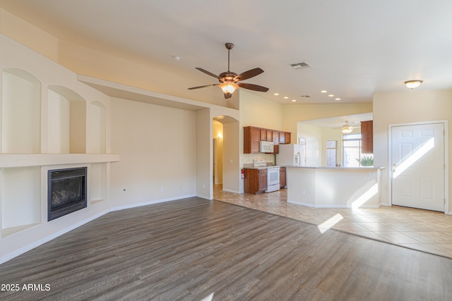 unfurnished living room featuring ceiling fan and light hardwood / wood-style flooring