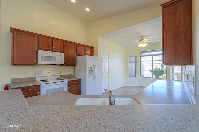 kitchen featuring ceiling fan, kitchen peninsula, sink, white appliances, and light stone countertops