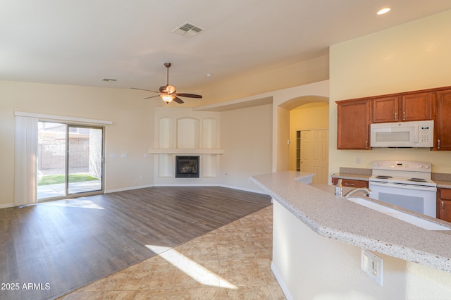 kitchen with ceiling fan, light hardwood / wood-style floors, light stone counters, and white appliances