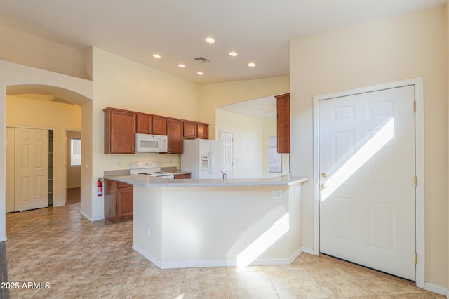 kitchen featuring lofted ceiling, kitchen peninsula, light stone countertops, and white appliances