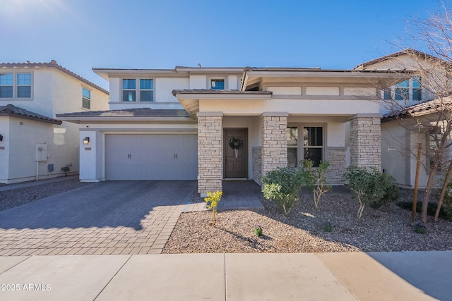 prairie-style house featuring a garage, decorative driveway, stone siding, and stucco siding