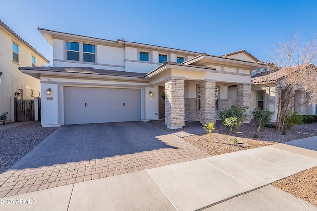 prairie-style house featuring a garage, decorative driveway, stone siding, and stucco siding