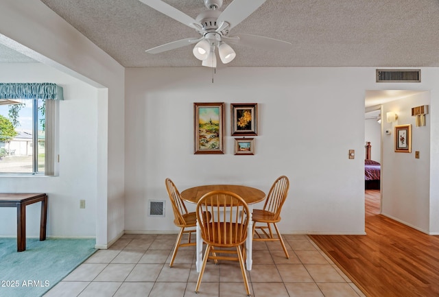 tiled dining space featuring a textured ceiling and ceiling fan