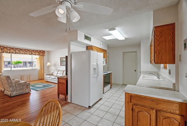 kitchen with white appliances, a textured ceiling, ceiling fan, sink, and light tile patterned floors