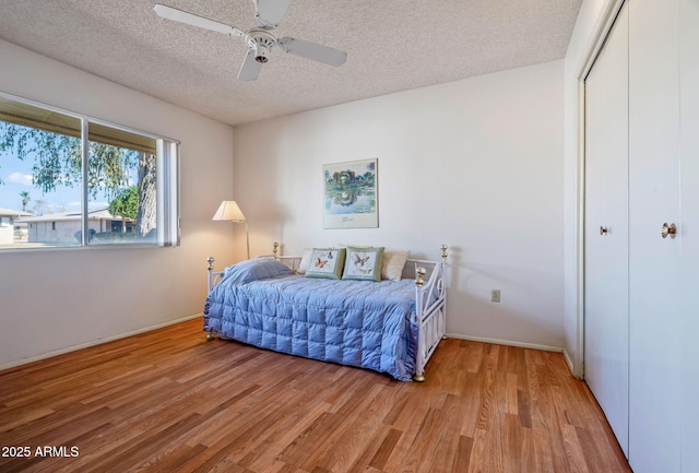 bedroom featuring ceiling fan, a closet, a textured ceiling, and light wood-type flooring