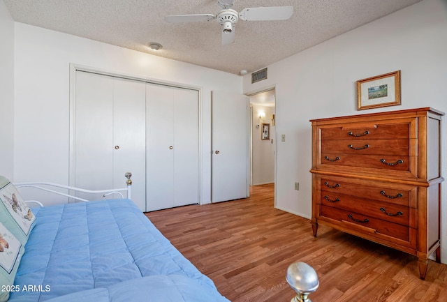 bedroom with a textured ceiling, a closet, ceiling fan, and light hardwood / wood-style floors