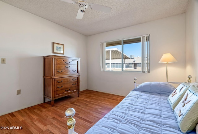 bedroom featuring ceiling fan, wood-type flooring, and a textured ceiling