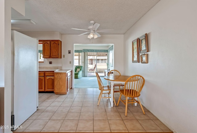 kitchen featuring ceiling fan, white fridge, light tile patterned flooring, and a textured ceiling