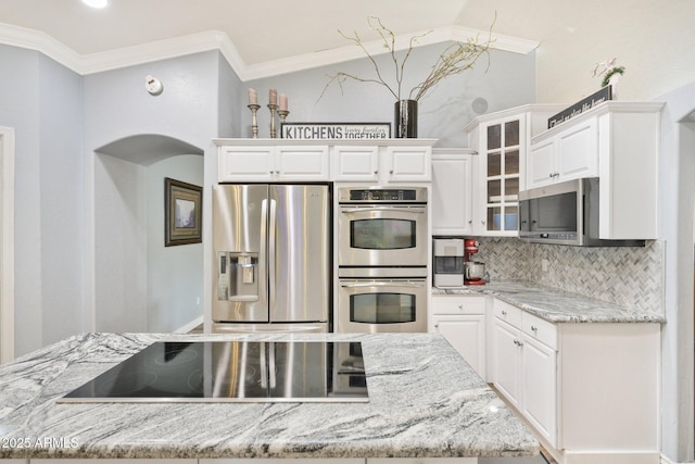 kitchen featuring appliances with stainless steel finishes, white cabinets, ornamental molding, decorative backsplash, and arched walkways